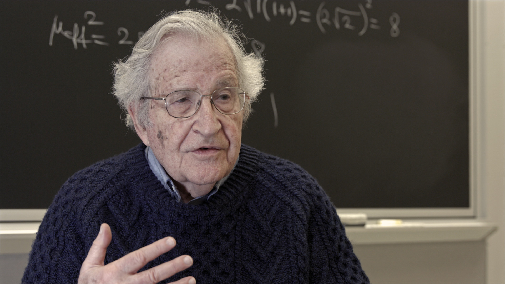 Disparity Film Still, Noam Chomsky in front of blackboard